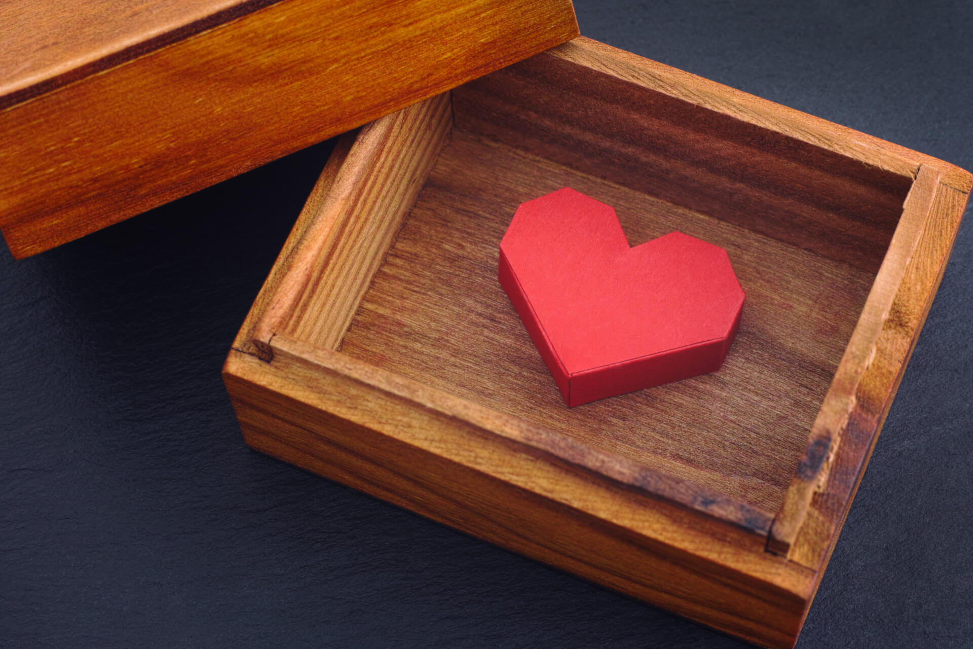 red paper origami heart inside wooden box